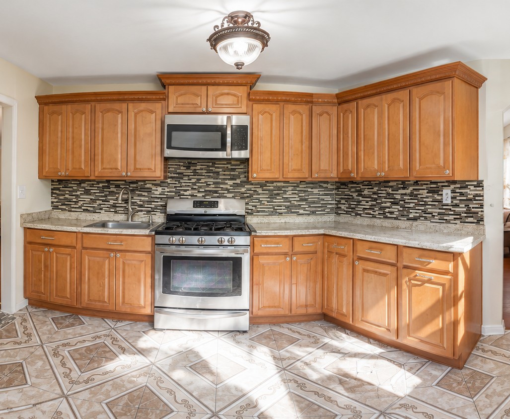 Kitchen with warm wood cabinetry, a mosaic backsplash and stainless steel appliances